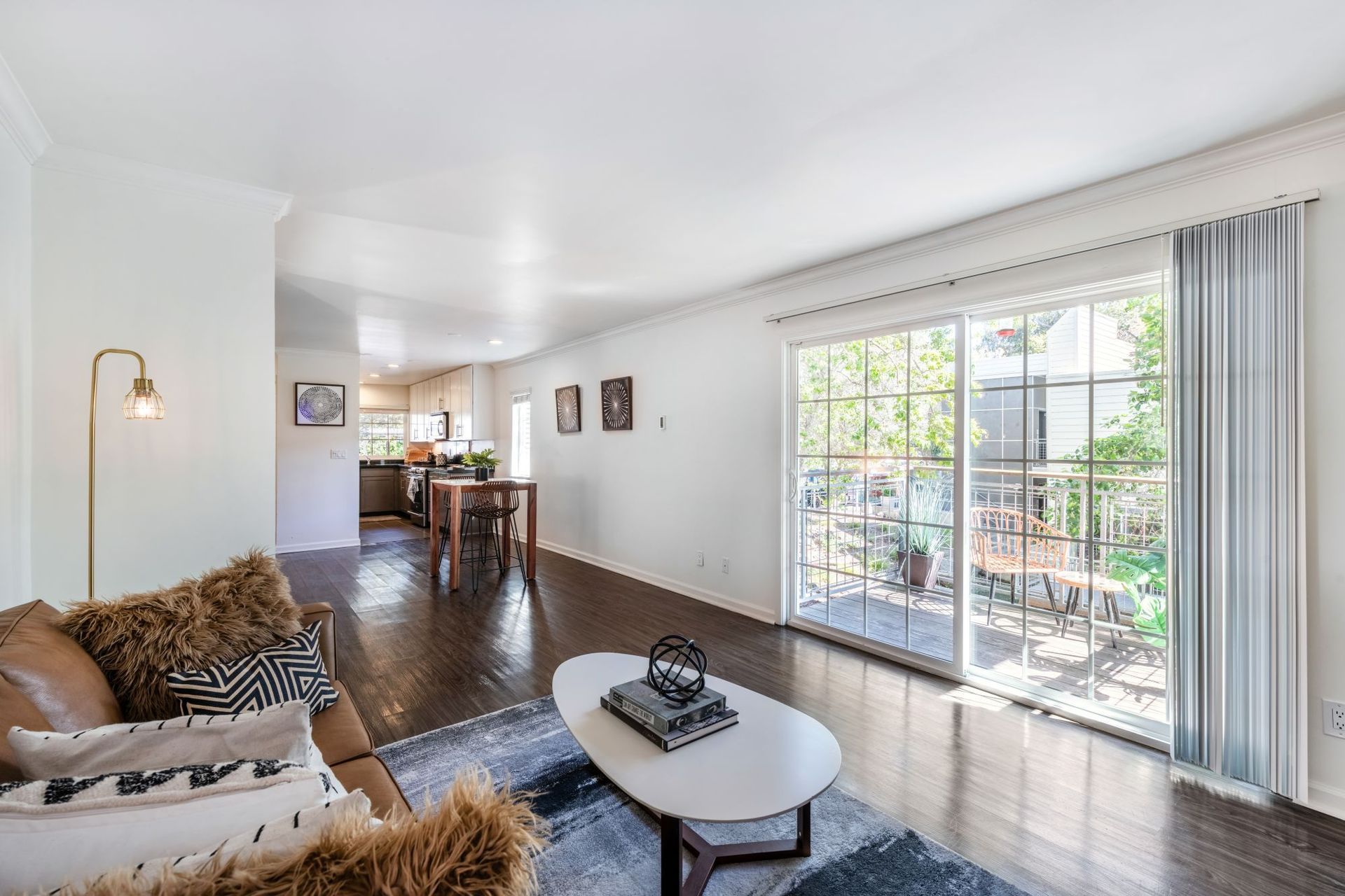 Bright living room with sofa, coffee table, dining area, and large sliding glass doors to a patio.