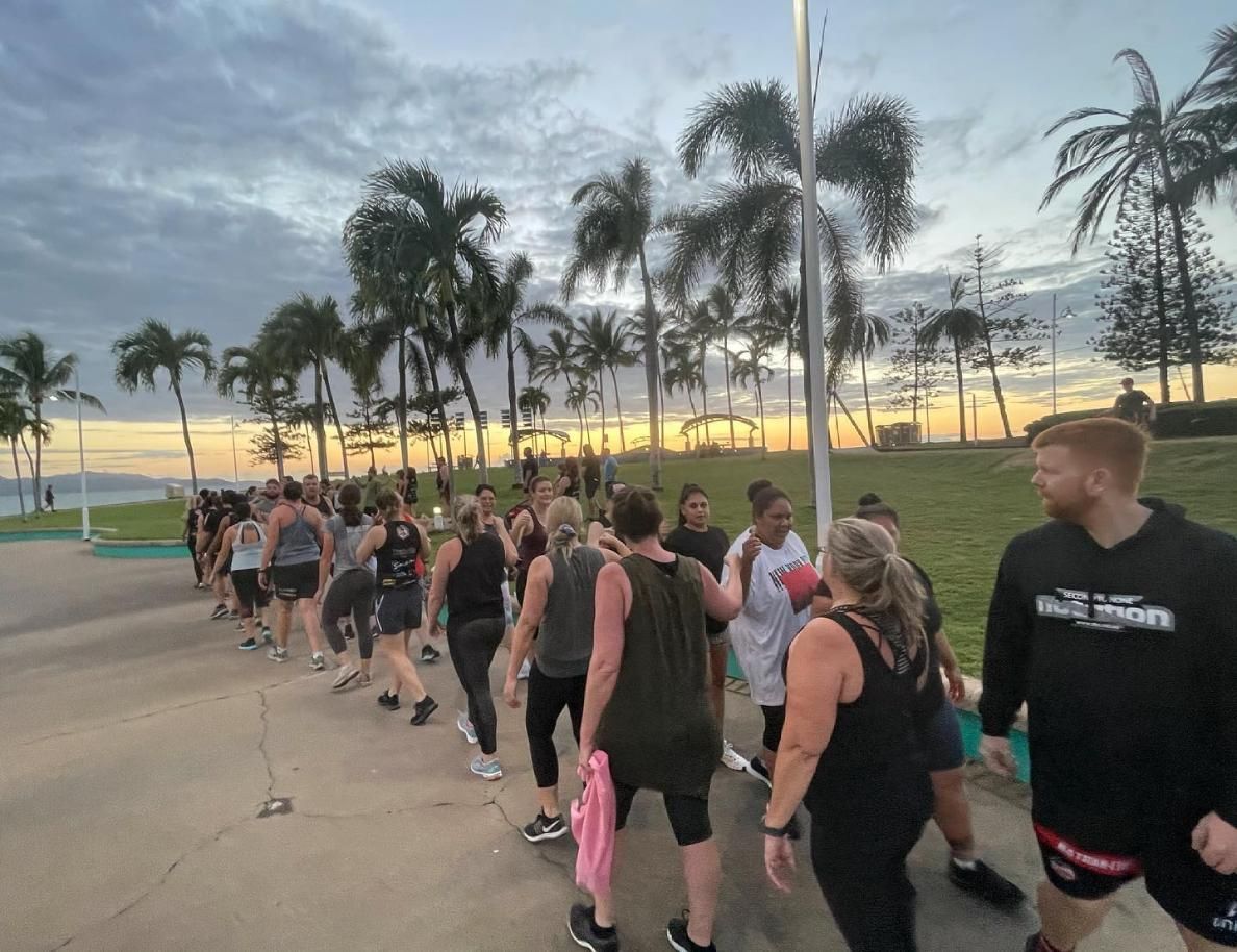 A Group Of People Are Walking Down A Sidewalk In Front Of Palm Trees — Elev8ed Fitness In Currajong, QLD