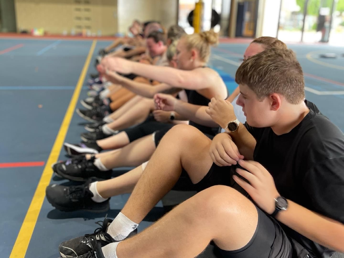 A Group Of People Are Sitting On The Floor With Their Legs Crossed — Elev8ed Fitness In Currajong, QLD