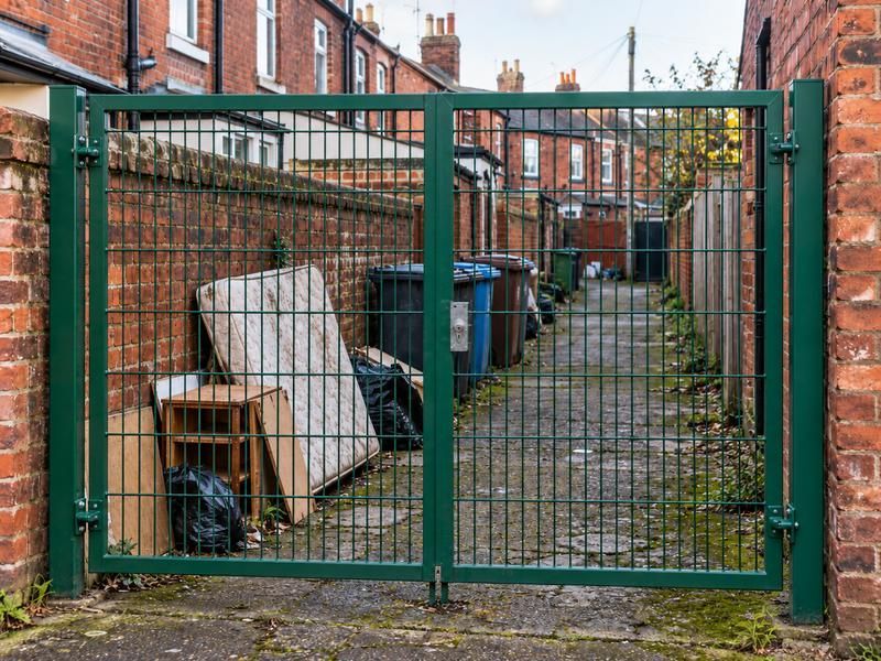 Mattress, bins and bags dumped behind a gated alleyway