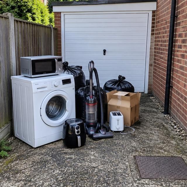 Before: a washing machine, microwave and vacuum left outside a garage