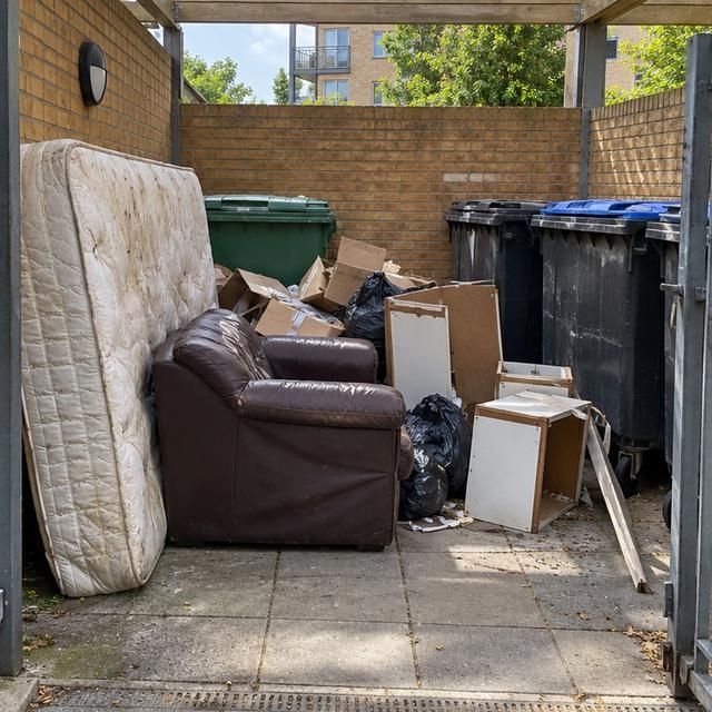Before: a bin store blocked with a sofa, mattress and bags