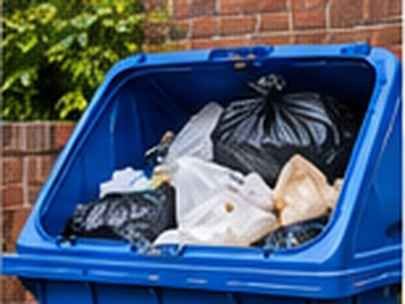 Overflowing communal bin with bags piled on top