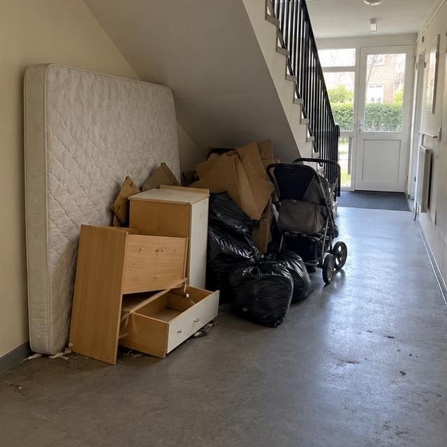 Before: a stairwell blocked with a mattress, boxes and a pushchair