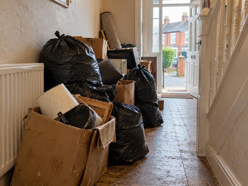 Hallway left full of bags, boxes and a rolled carpet