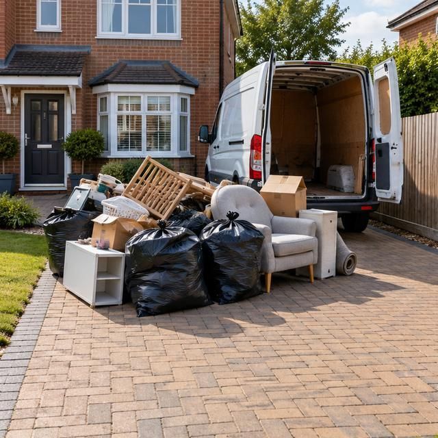 Before: bags, boxes and furniture piled on a driveway beside a van