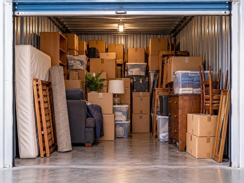 Storage unit full of boxes, furniture and a mattress