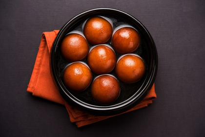 Seven orange sweets in a black bowl on a folded orange napkin against a dark background