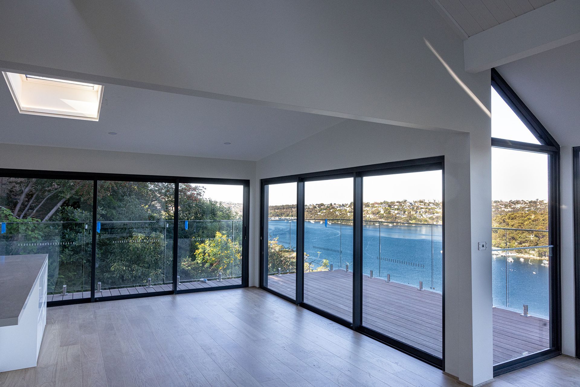 A large empty room with lots of windows overlooking a body of water.