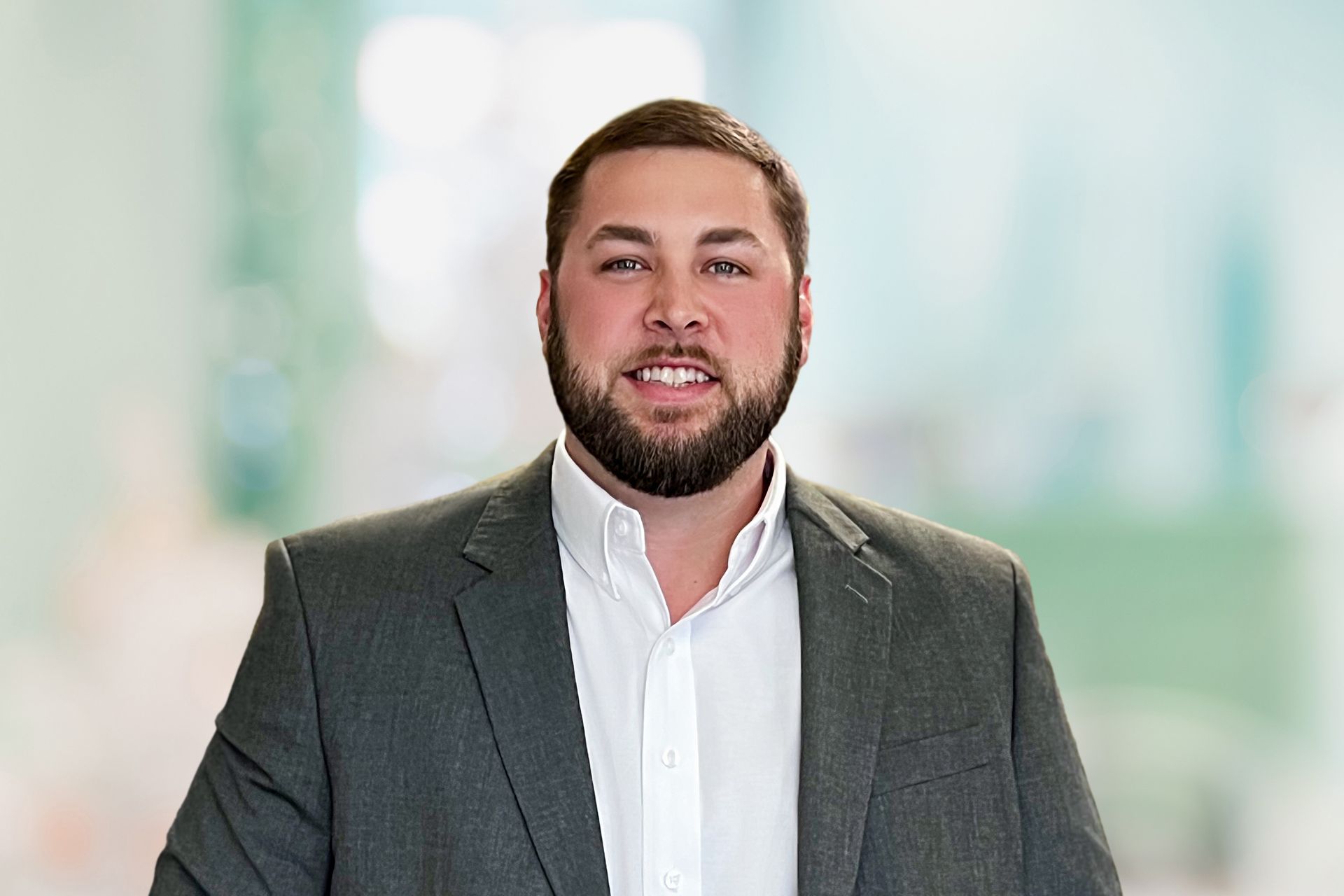 A man with a beard is wearing a suit and a white shirt.