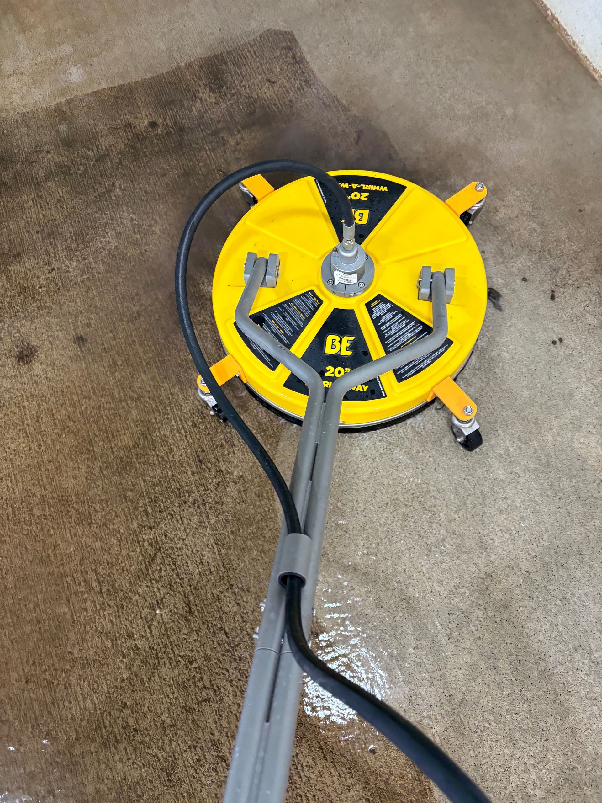 Yellow DEWALT pressure washer on concrete with a gray spray wand and hose attached