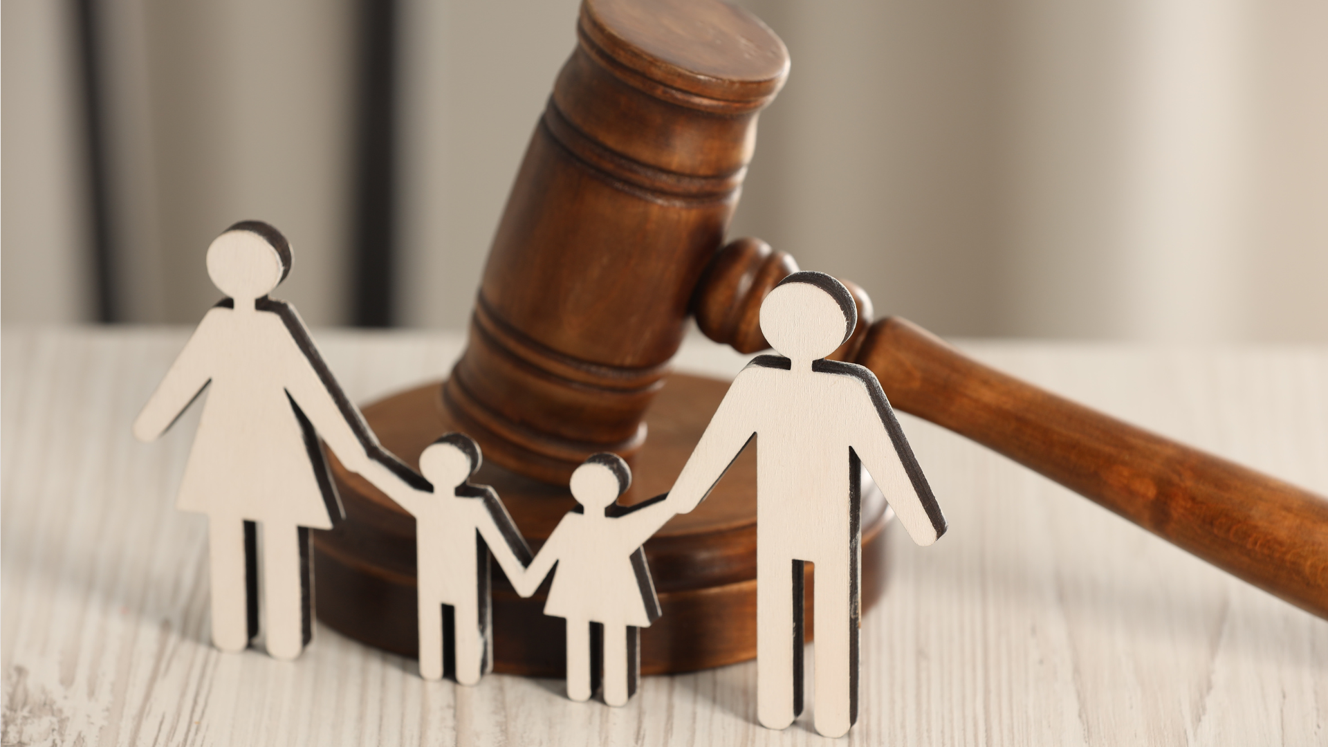 Wooden family figures with a gavel on a light-colored surface.