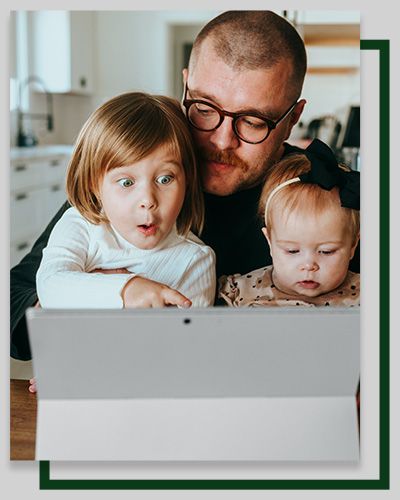 Man with two children looks at a laptop with surprised expressions in a kitchen setting.