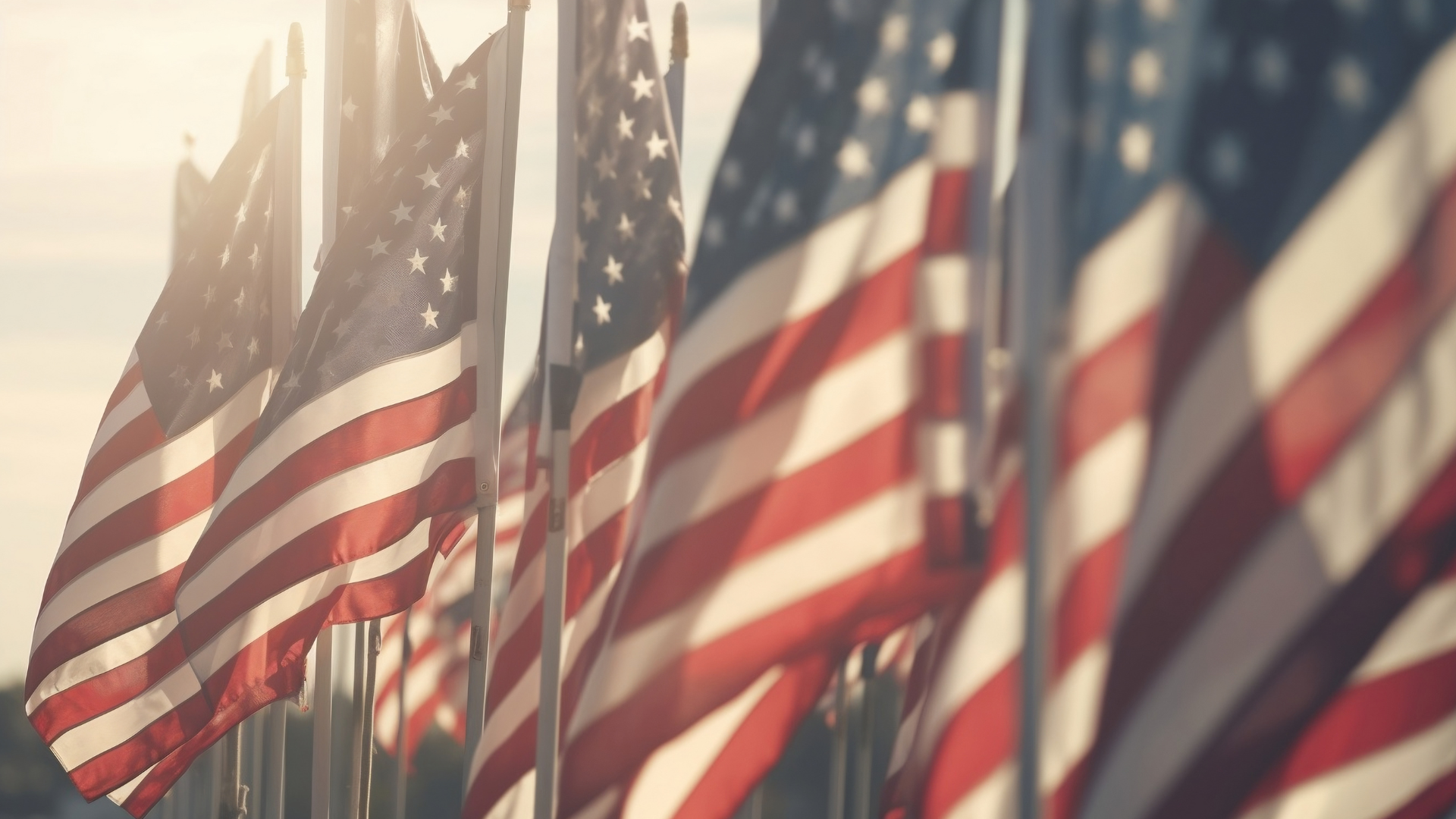 American flags waving in the wind, backlit by sunlight.
