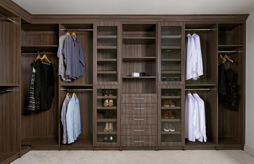 Built-in wooden closet with hanging shirts, jackets, and folded shelves in the center.