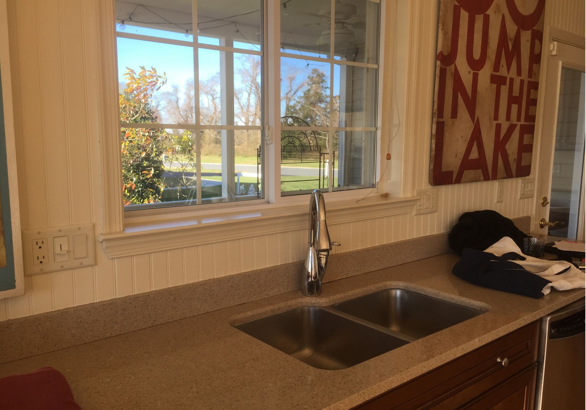 Kitchen sink beneath a window with a lake view and a decorative wall sign.