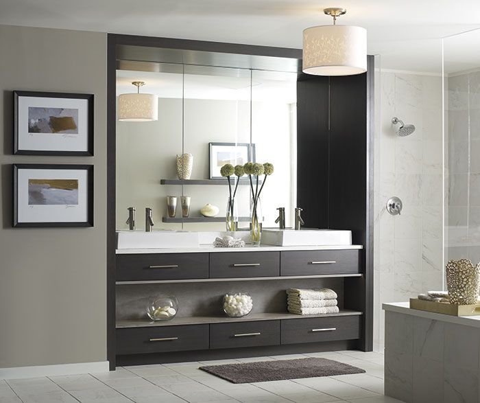 Modern bathroom with dark vanity, large mirror, framed wall art, and glass shower stall.