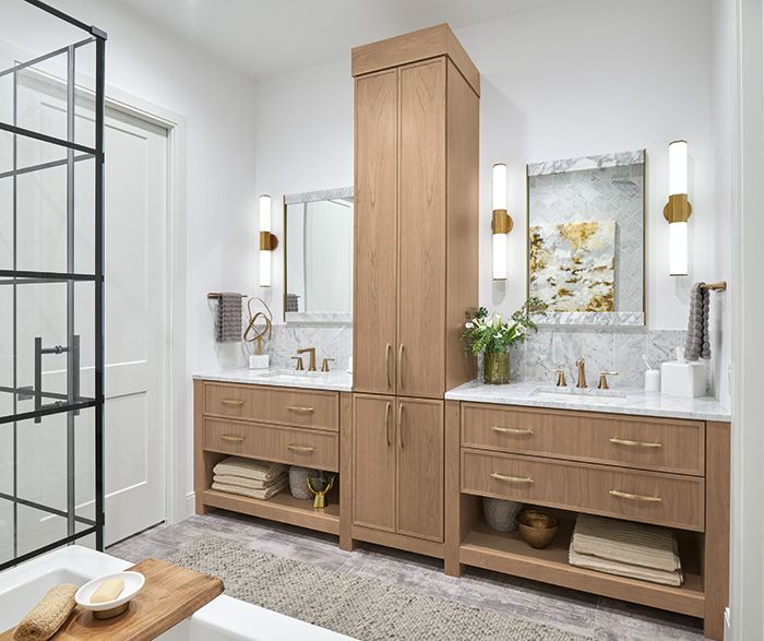 Modern bathroom with dual wood vanities, large mirrors, wall sconces, and a glass shower enclosure