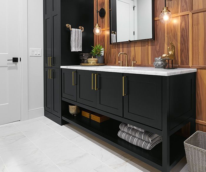 Modern bathroom vanity with black cabinets, white countertop, wood accent wall, and mirror.