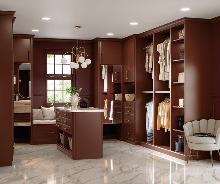Luxurious dark-wood walk-in closet with built-in shelves, hanging clothes, and marble flooring