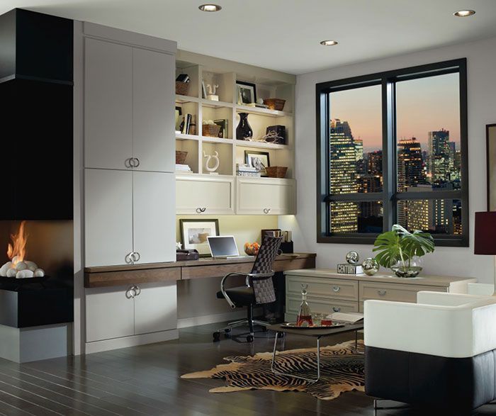 Modern home office with desk, shelves, fireplace, and city skyline at sunset through large windows