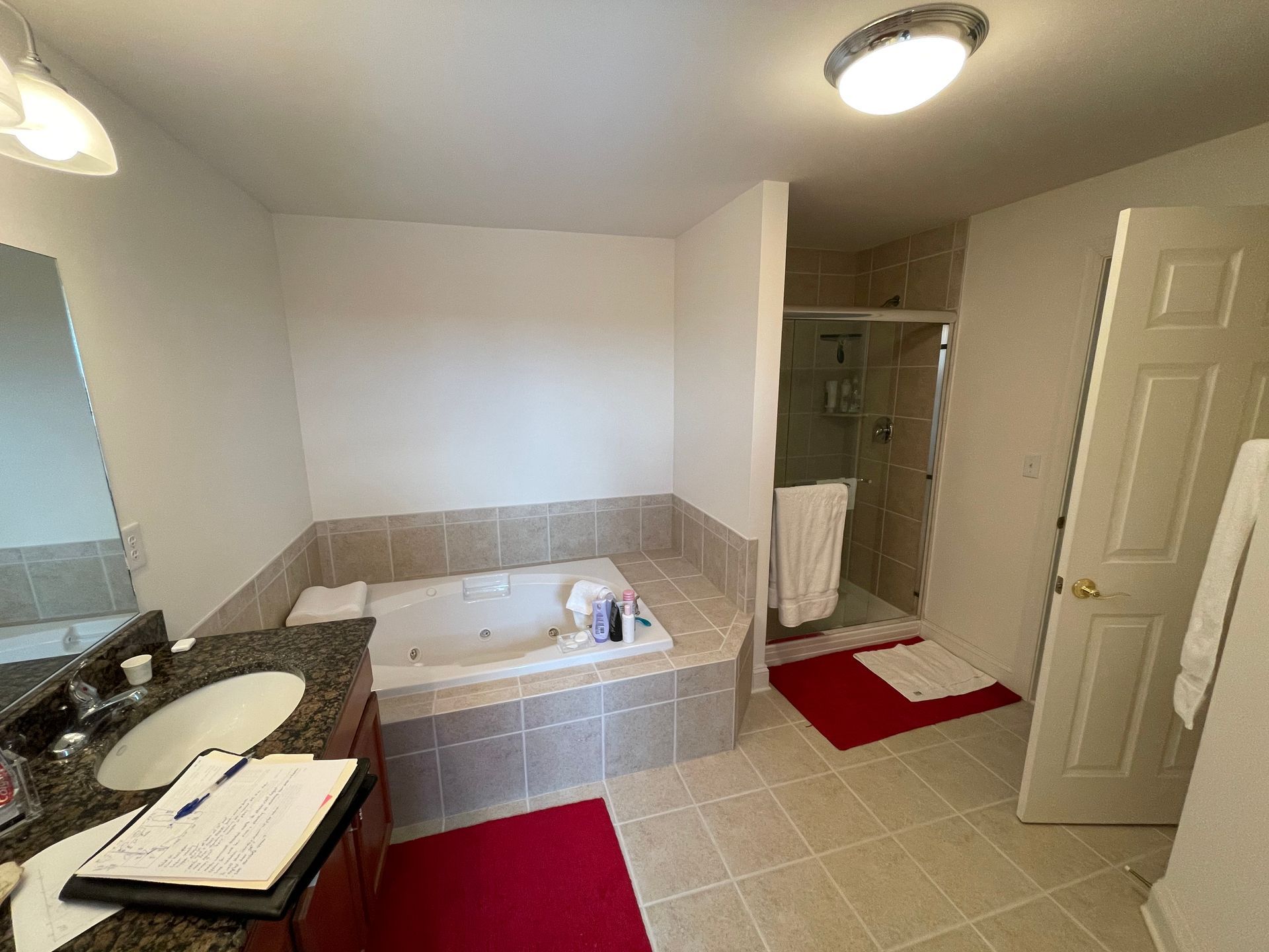 Bathroom with a vanity sink, bathtub, toilet, and tiled floor in neutral tones.