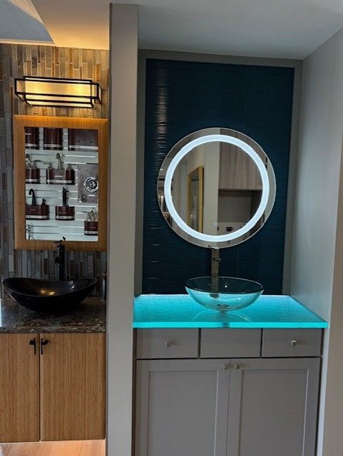 Modern bathroom vanity with round lit mirror, turquoise countertop, and wood accents