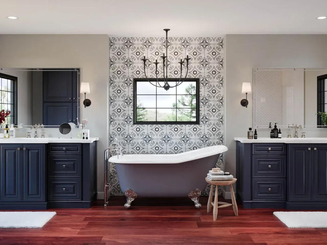 Elegant bathroom with twin navy vanities, patterned accent wall, clawfoot tub, and black chandelier.