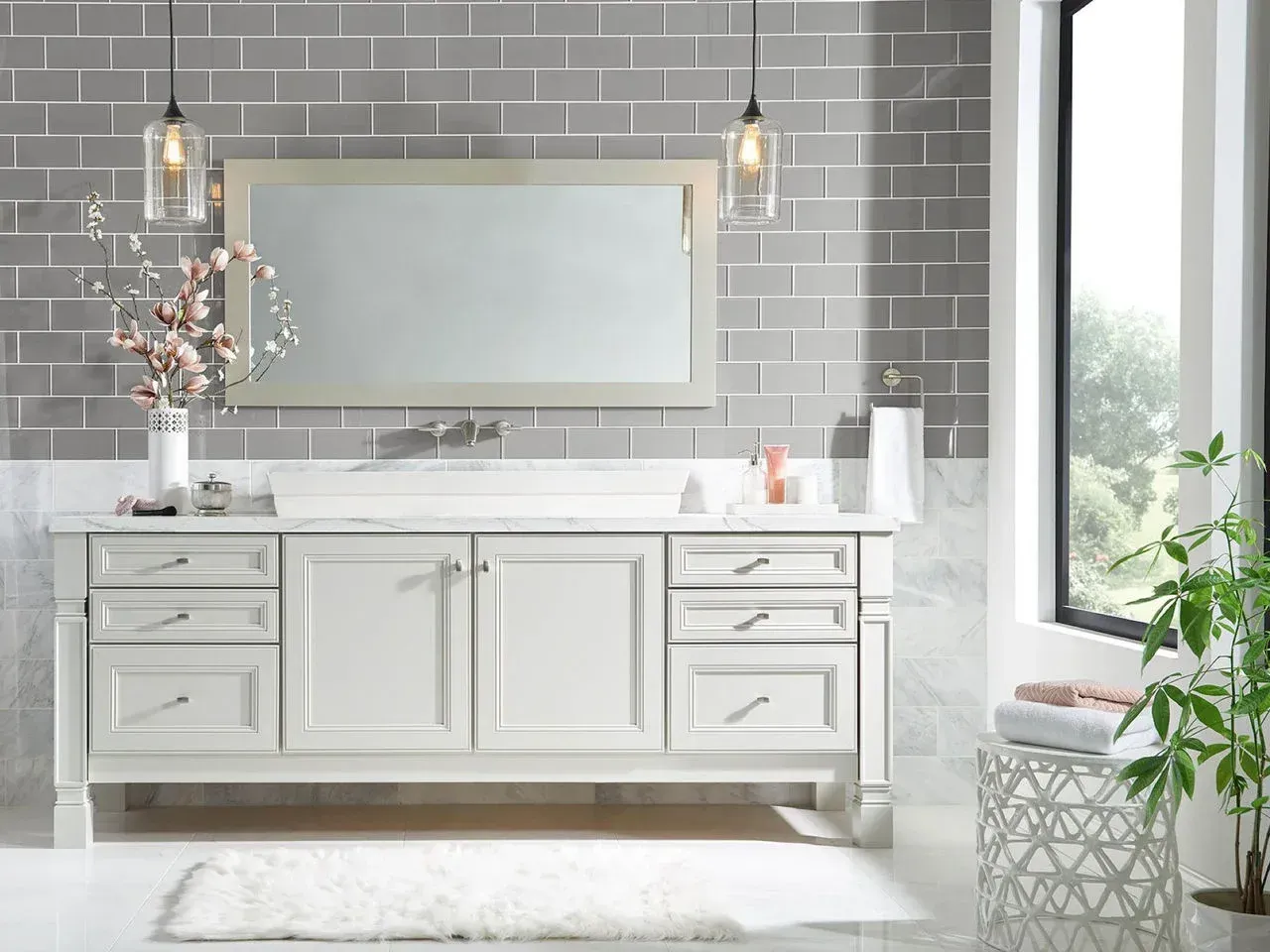 Bright modern bathroom with white vanity, gray tile wall, large mirror, and hanging pendant lights.