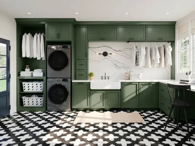 Modern laundry room with green cabinets, black-and-white tiled floor, washer-dryer, and sunlit window.