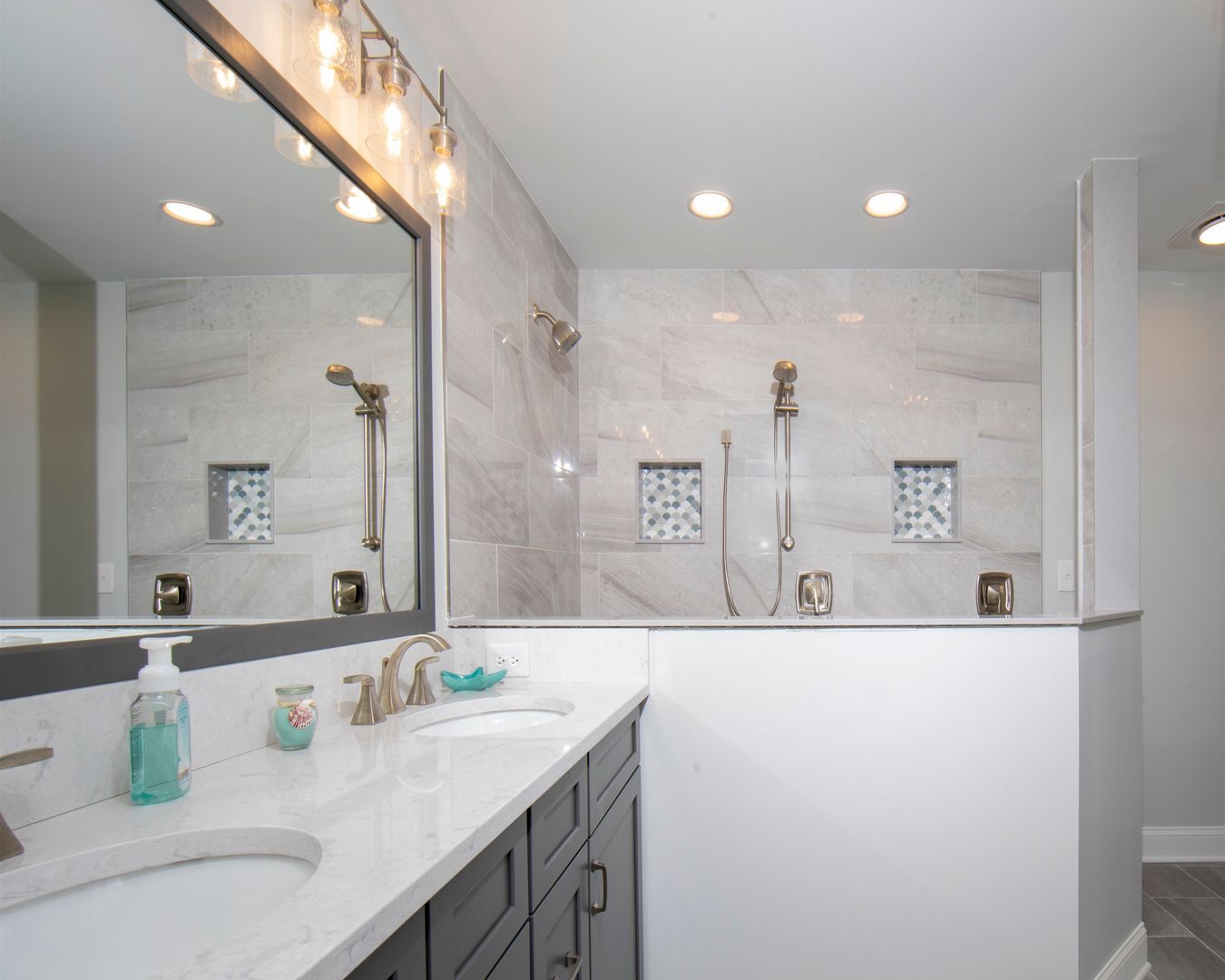 Bright modern bathroom with marble vanity, large mirror, and glass shower enclosure