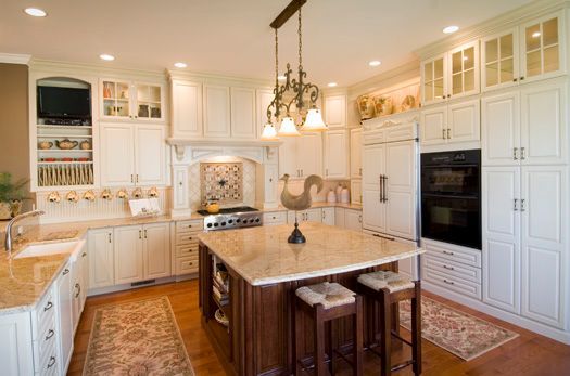 Bright white luxury kitchen with a large island, built-in oven, and warm pendant lighting