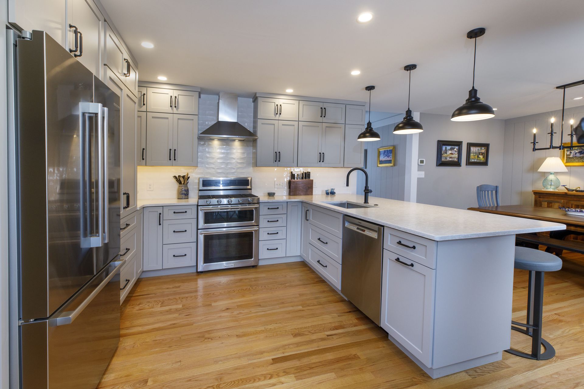 Bright modern kitchen with stainless steel appliances, white cabinets, and a large island with pendant lights