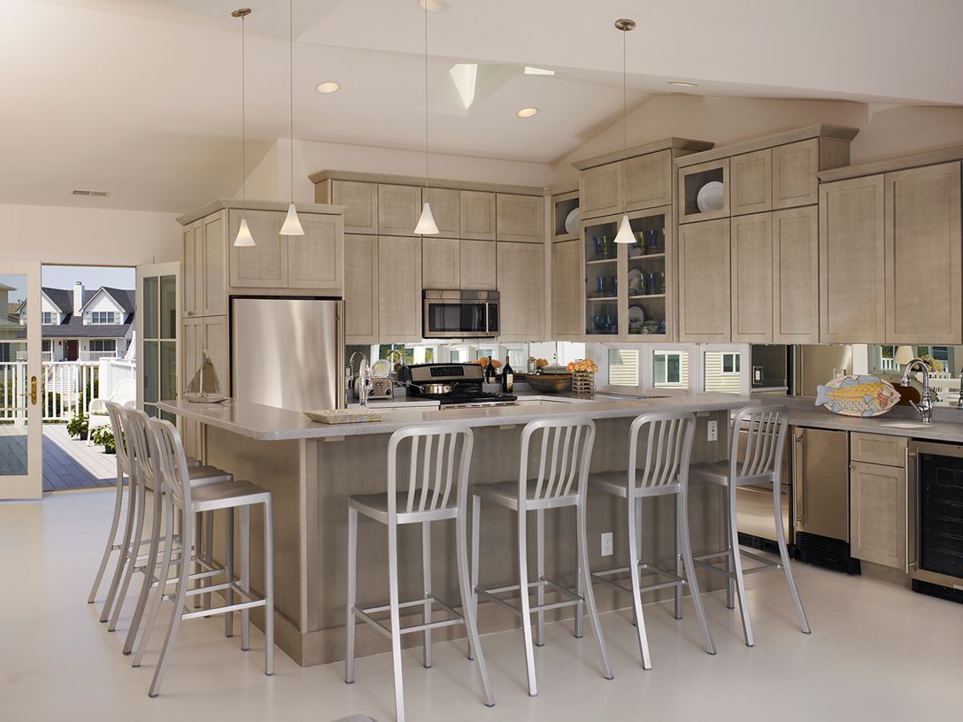 Bright modern kitchen with island, white bar stools, stainless appliances, and pendant lights