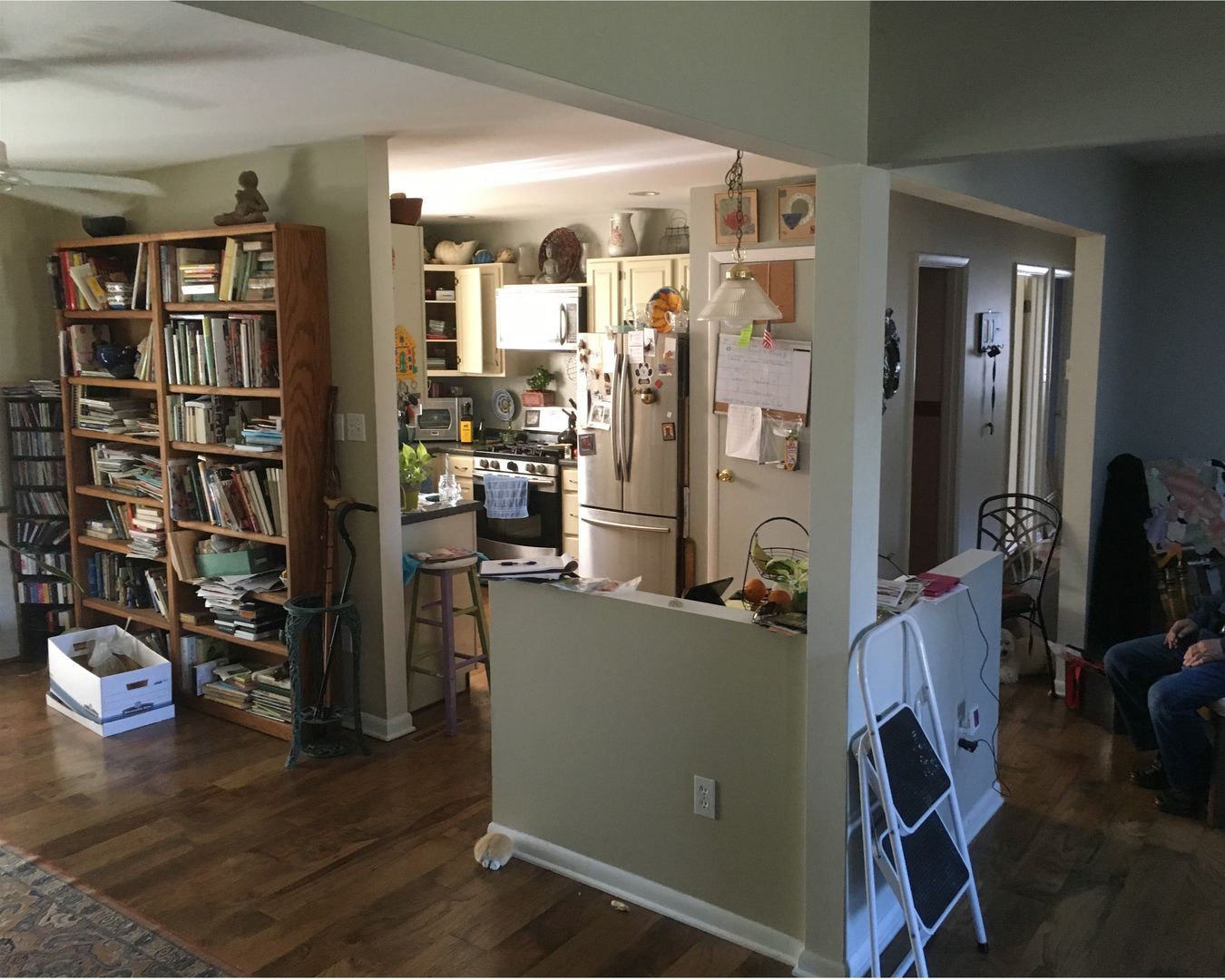 Living room with bookshelves, kitchen pass-through, and hardwood floors in a home interior