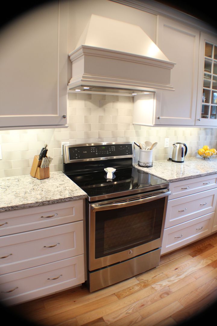 Modern kitchen with stainless steel range, white cabinets, granite counters, and hardwood floor