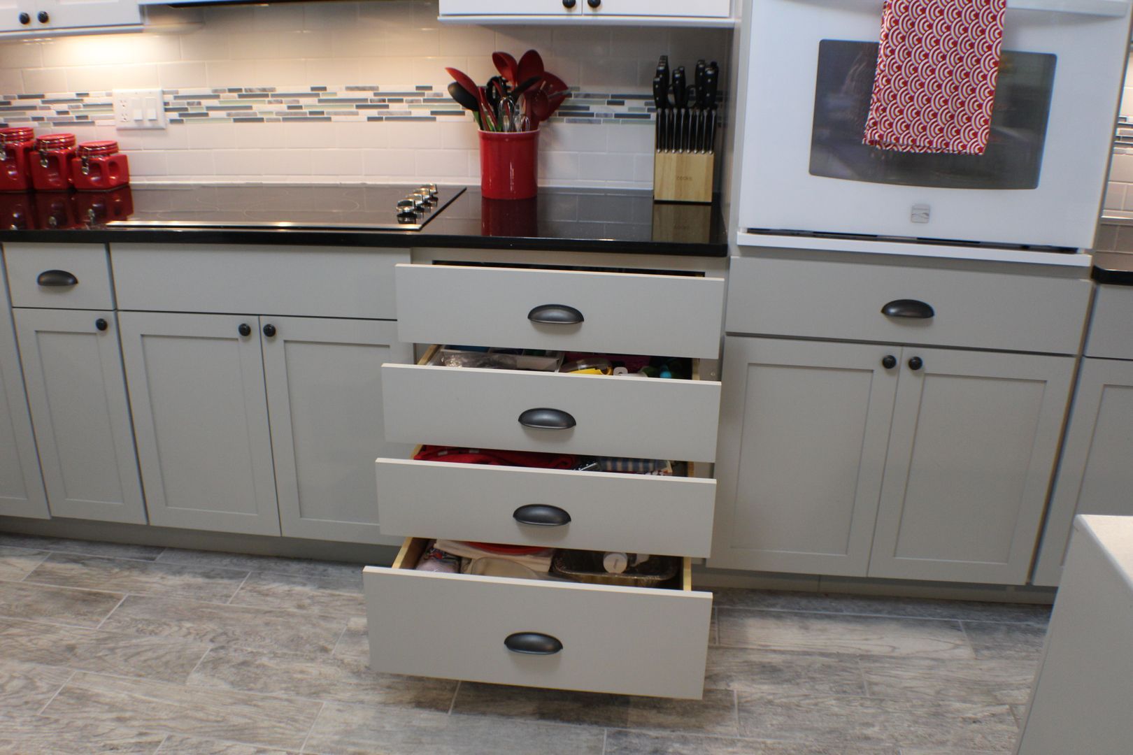 Kitchen cabinets with an open drawer stack, showing organized utensils and dishes.