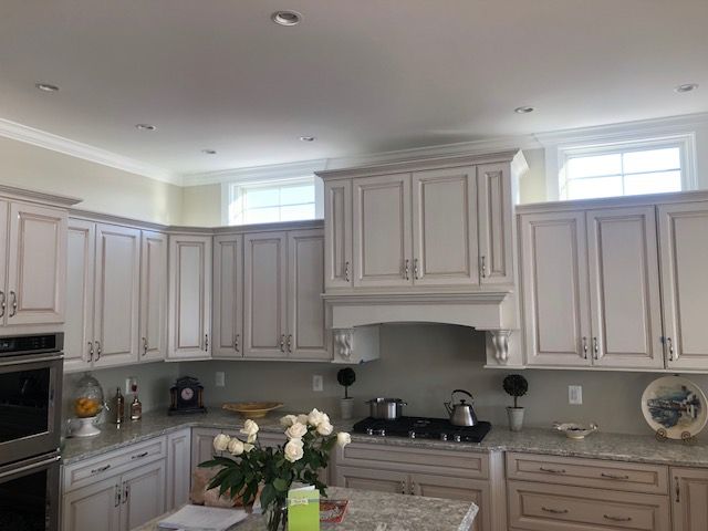 Bright, modern kitchen with light gray cabinets, stainless appliances, and flowers on the island.