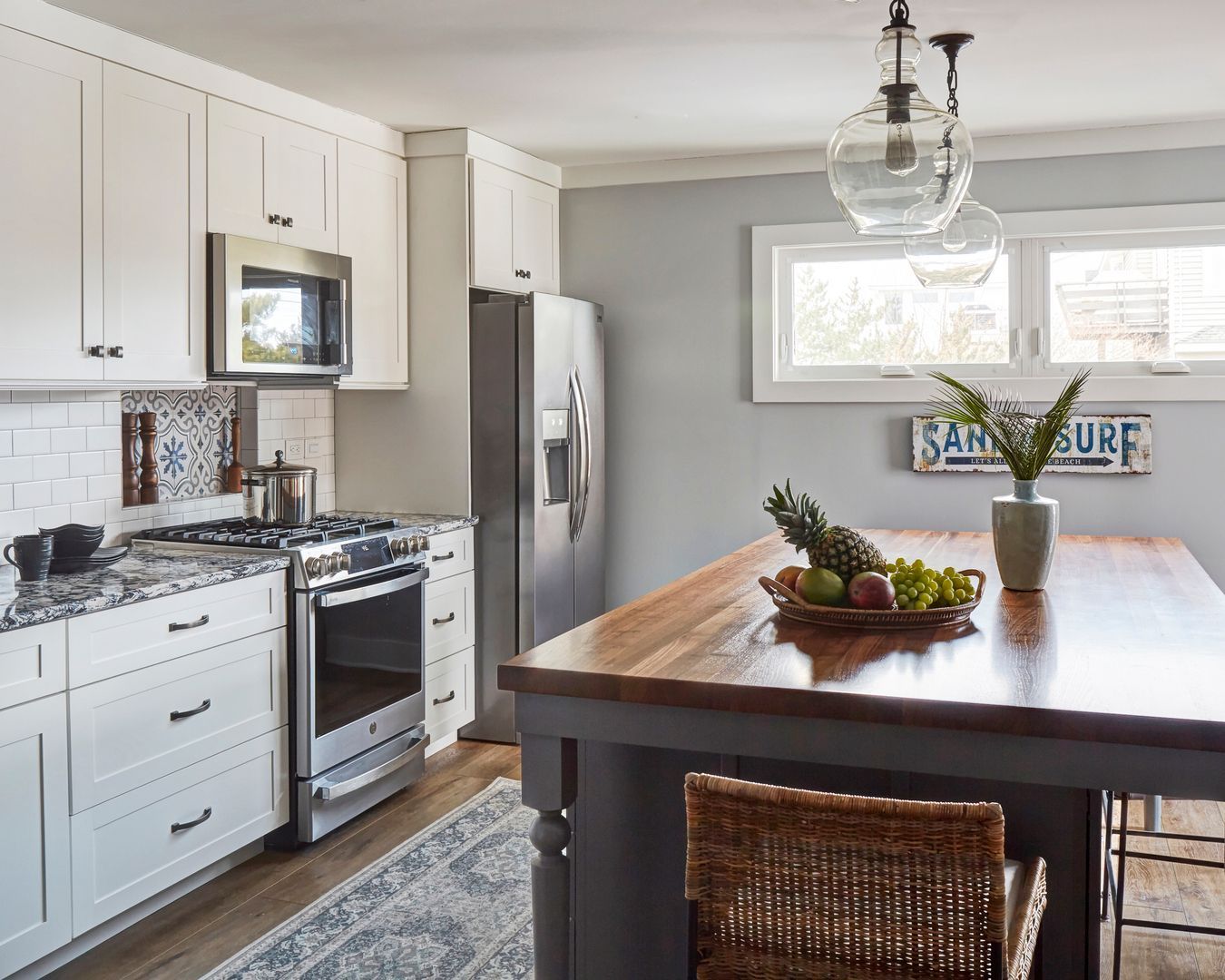 Bright kitchen with white cabinets, stainless appliances, and a dark wood island centerpiece.