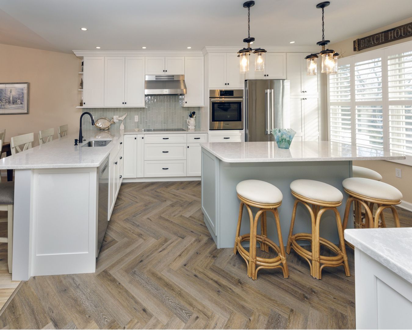 Bright modern white kitchen with island, pendant lights, bar stools, and herringbone wood floor