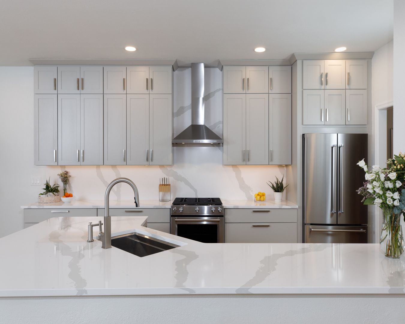 A kitchen with white cabinets , stainless steel appliances , a sink , and a refrigerator.
