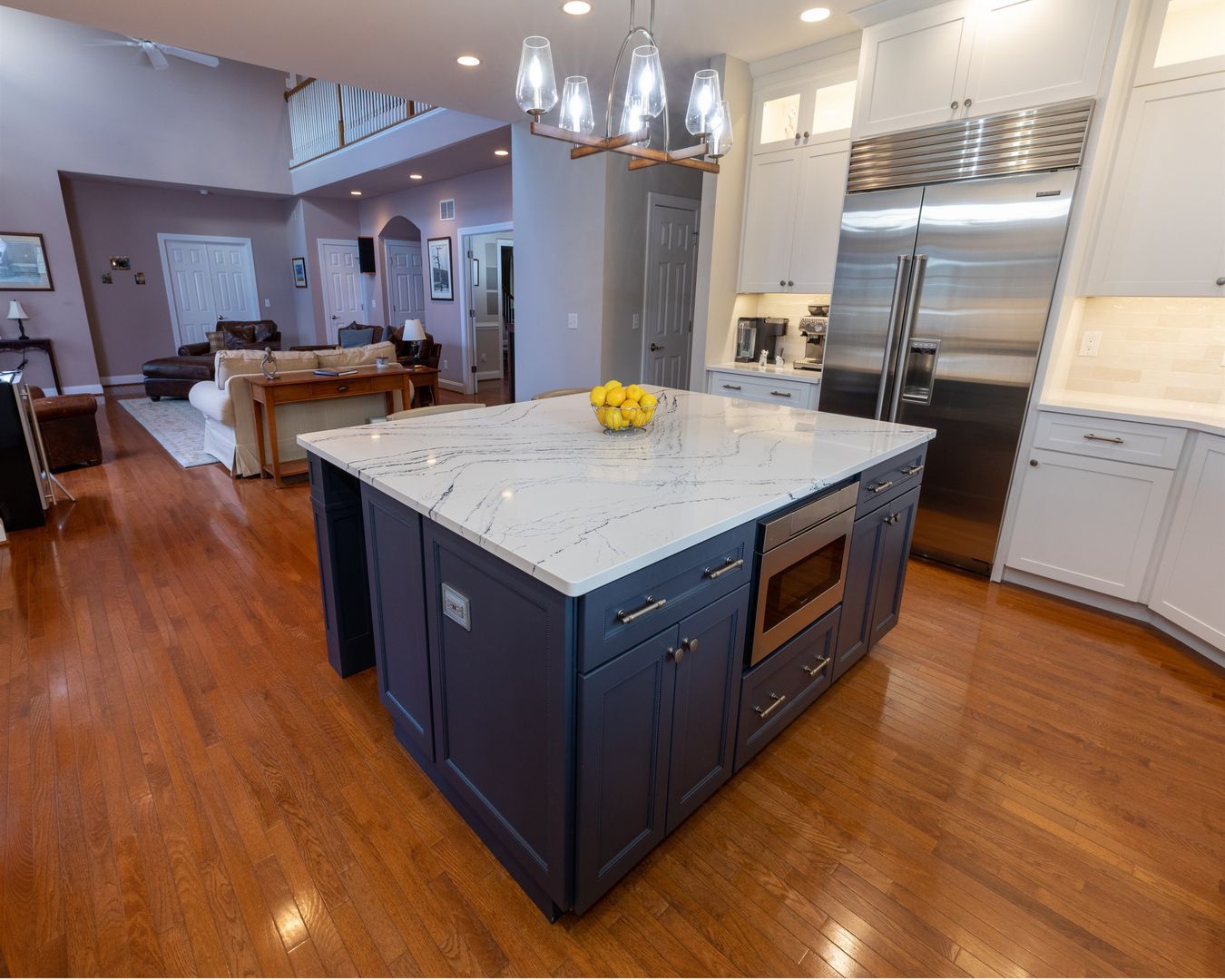 Modern kitchen with navy island, marble countertop, pendant lights, and hardwood floors