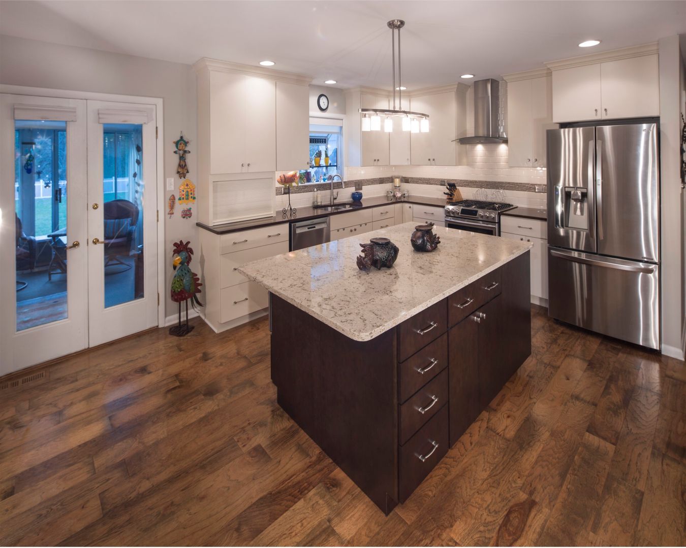 Modern kitchen with dark wood island, granite countertops, stainless steel fridge, and hardwood floors