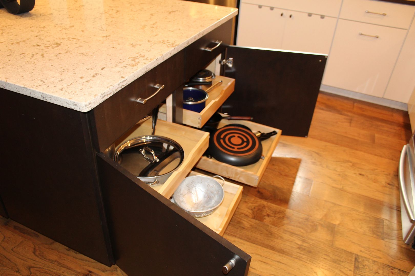Open kitchen cabinet with drawers pulled out, showing cookware and a stovetop burner inside.