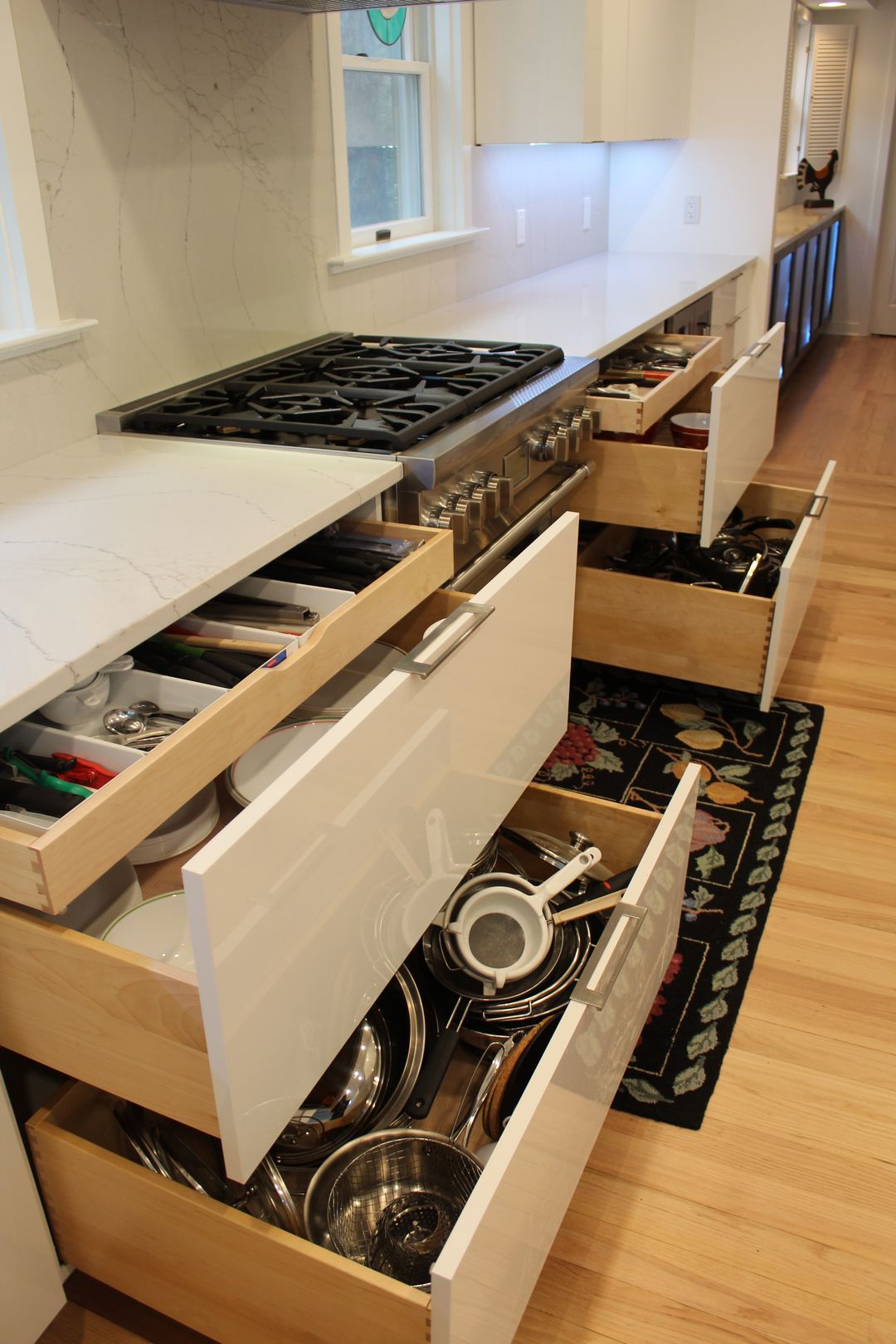 Open kitchen with white cabinets and drawers pulled out, revealing pots and utensils.