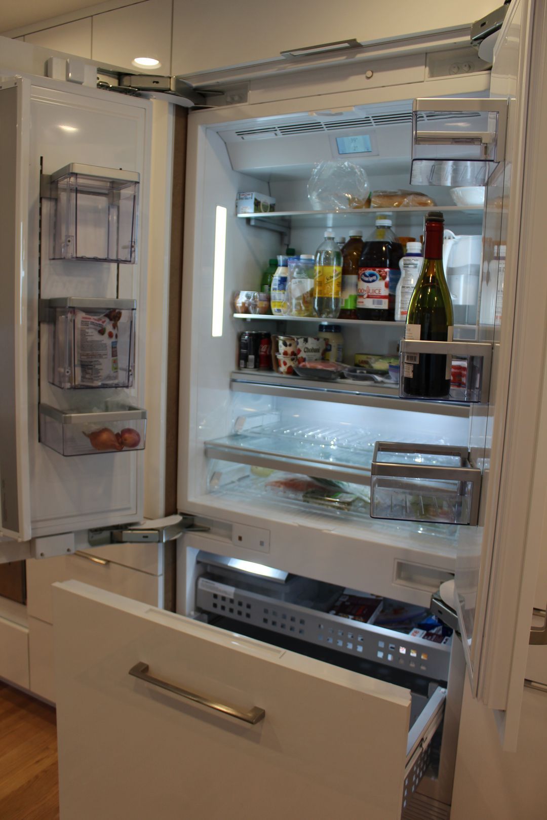 Open refrigerator with drawers pulled out and shelves stocked with food and bottles