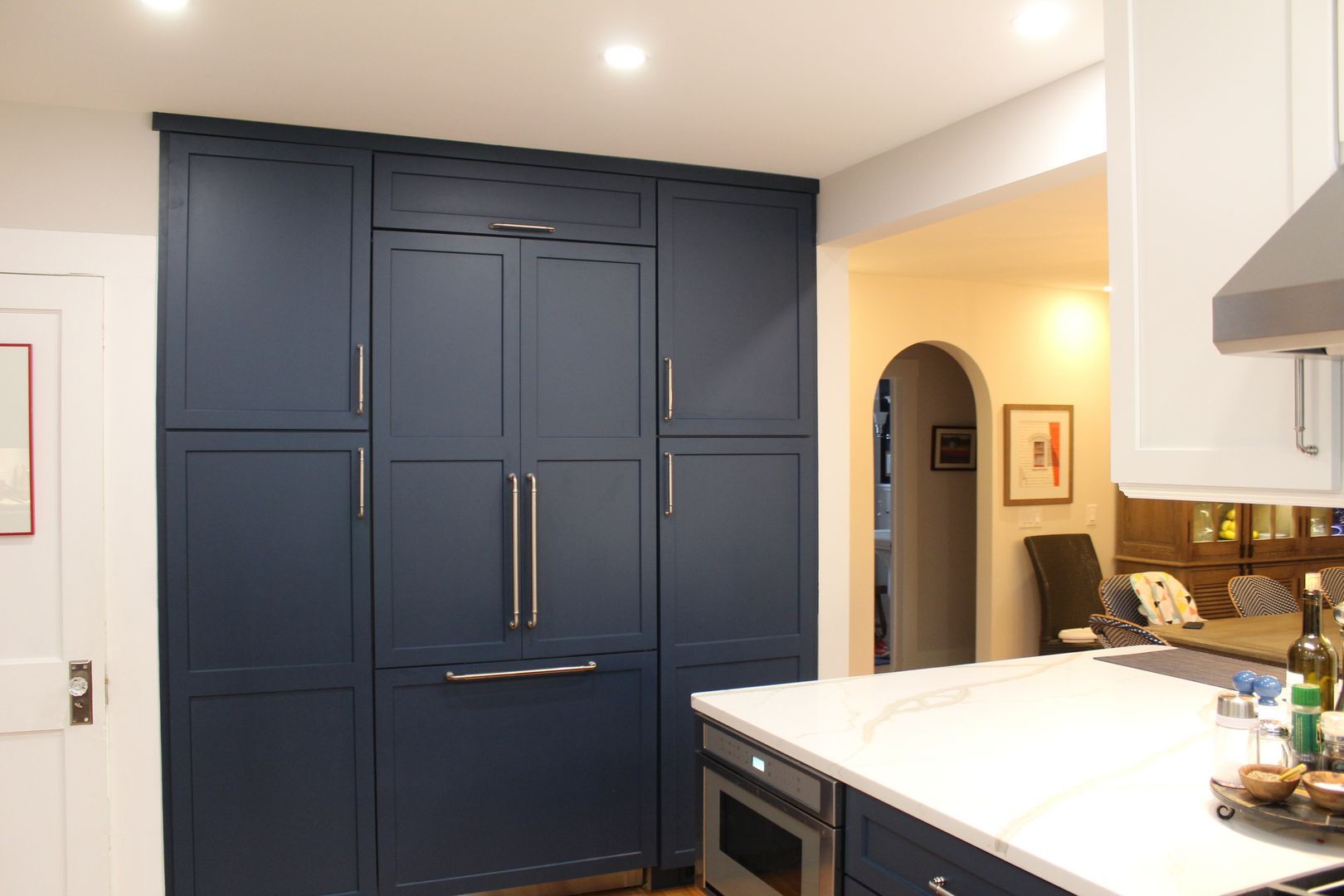Modern kitchen with navy built-in cabinets, white countertop, and arched doorway