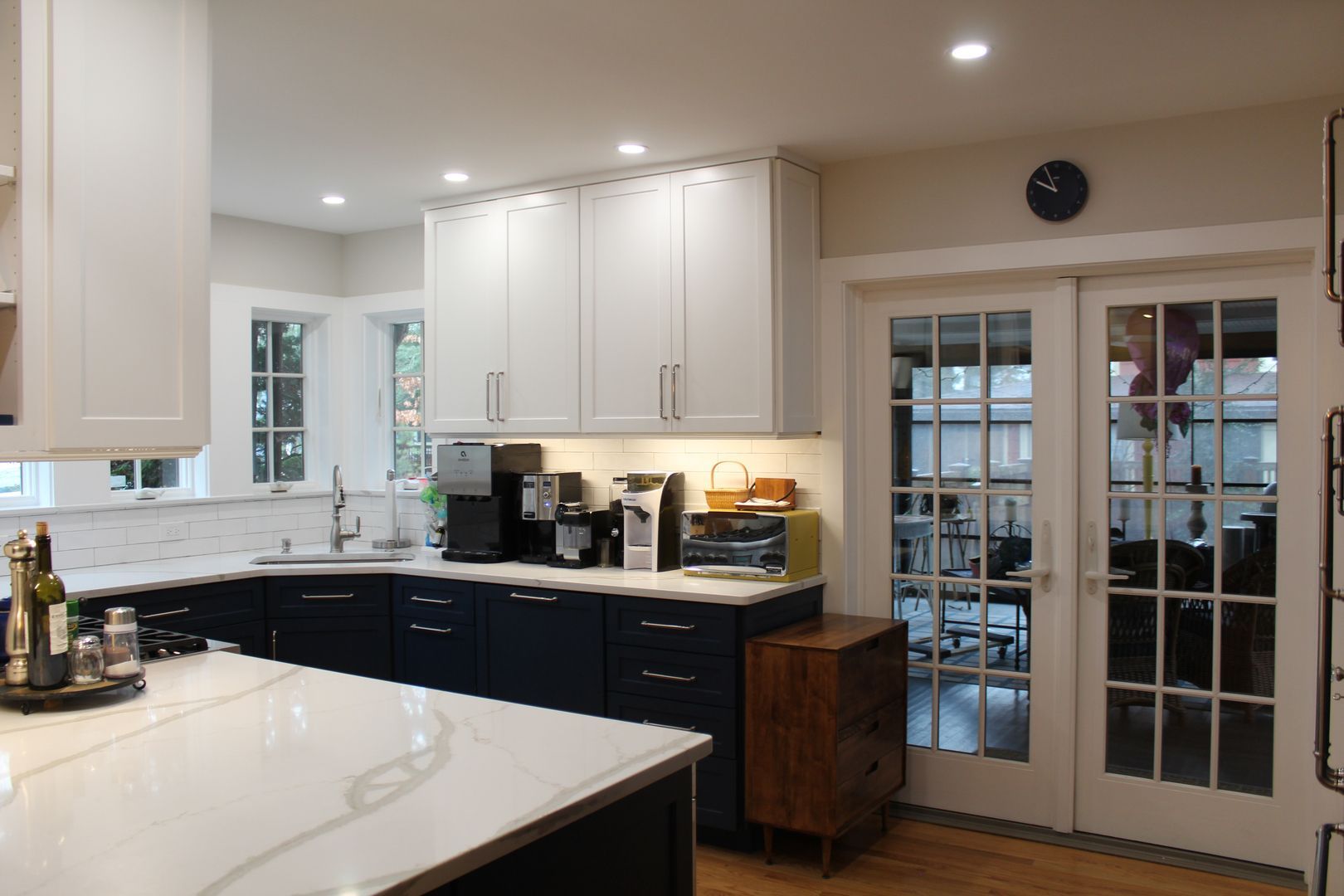 Bright modern kitchen with white cabinets, black counters, and glass French doors.
