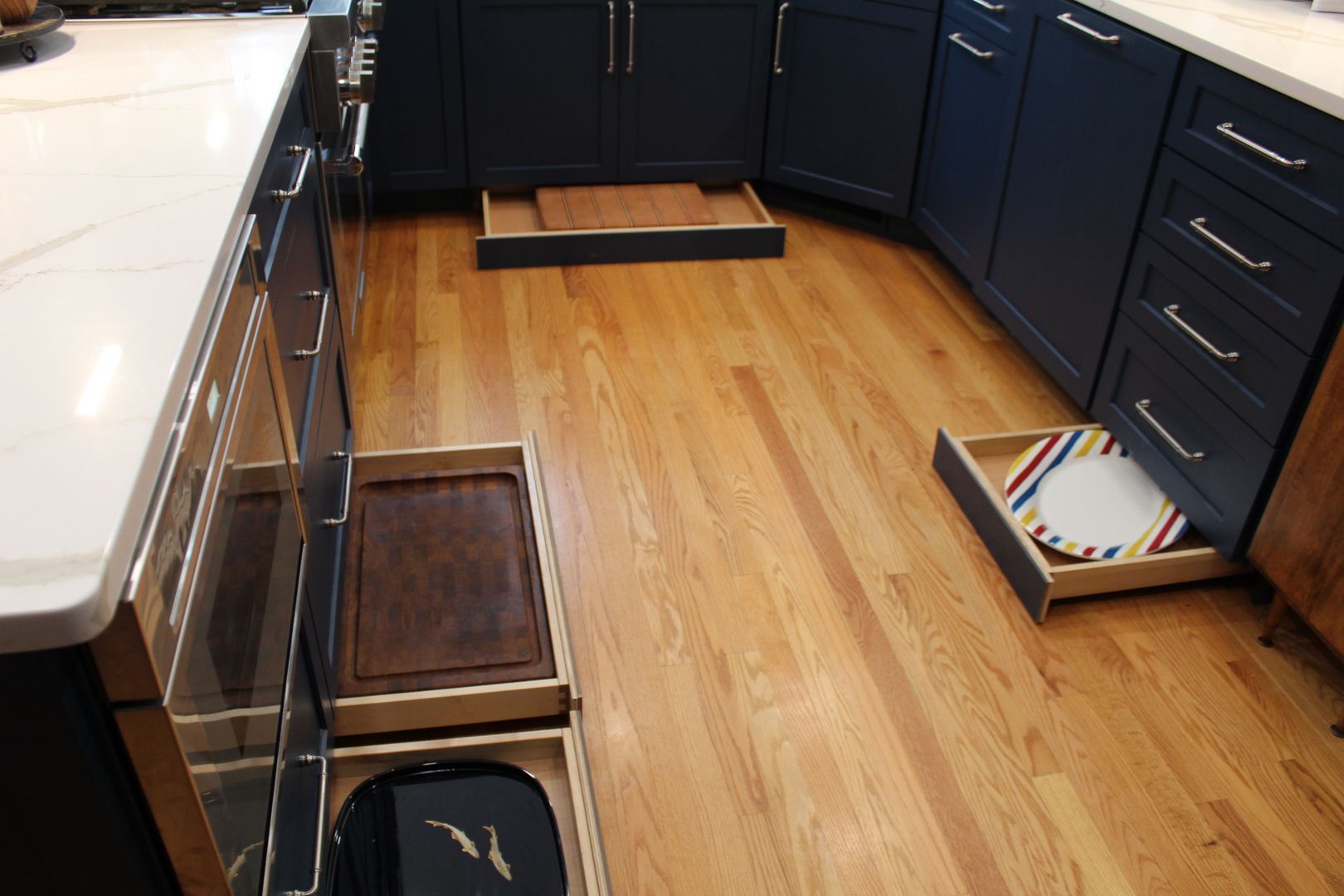 Kitchen with dark cabinets, hardwood floor, and two pet feeding drawers with bowls pulled out.