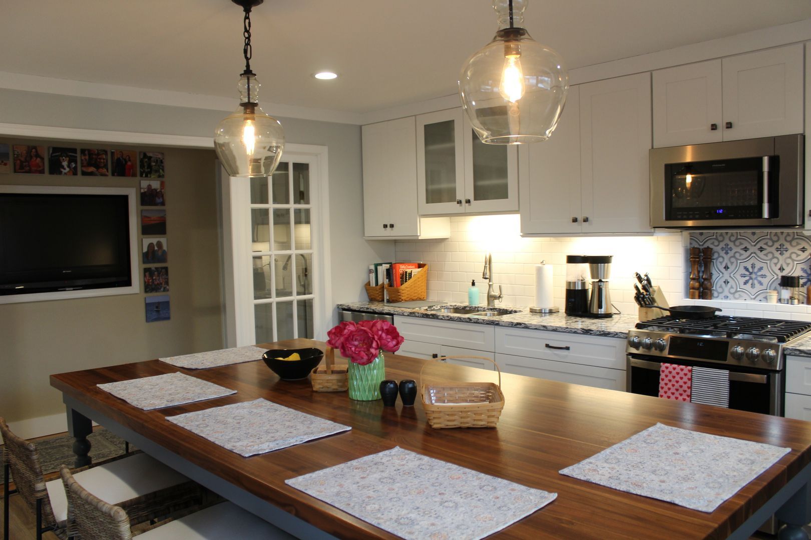 Modern kitchen with white cabinets, black appliances, and a wooden island set for dining.